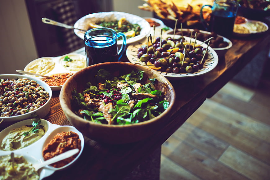 Rustic wooden table with Mediterranean mezze platter and salads