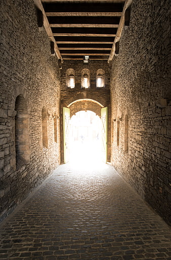 Medieval stone gate with cobblestone path and bright light