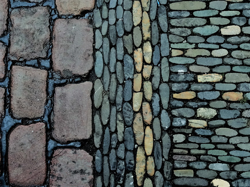 Top-down view of wet cobblestone and brick pavement texture