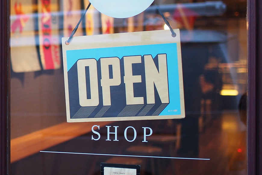 Open sign hanging in a shop window with blurred interior