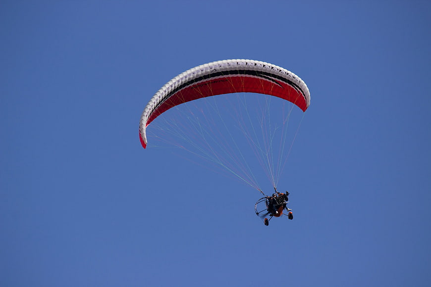 Motorized Paraglider Flying Against Clear Blue Sky