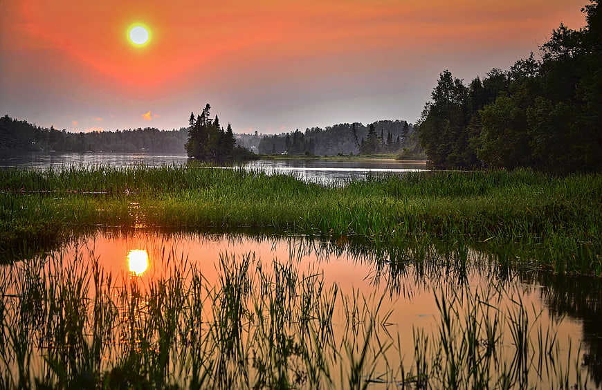 Vibrant Sunset Over Lake With Reeds and Reflection