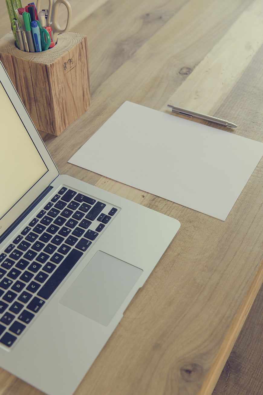 Minimalist Workspace with Laptop and Blank Paper on Wooden Desk