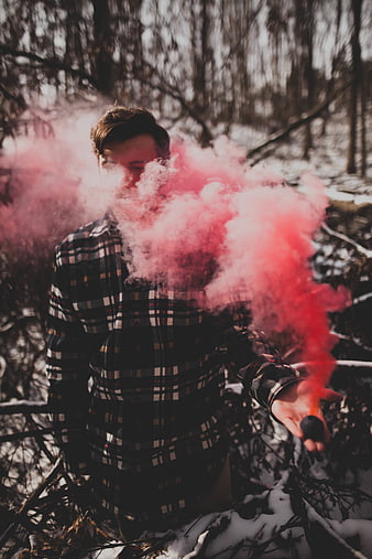 Man holding pink smoke grenade in snowy winter forest