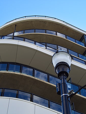 Low angle view of curved modern building with street lamp