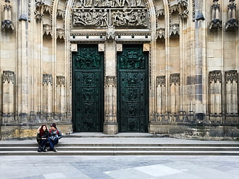 Couple sitting on steps before ornate Gothic cathedral doors