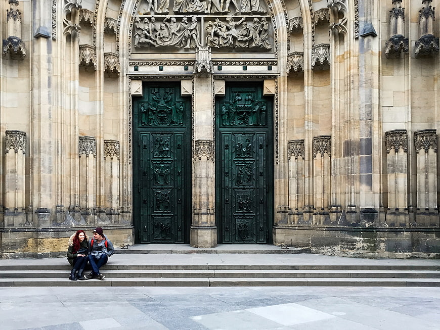 Couple sitting on steps before ornate Gothic cathedral doors