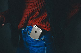 Silver iPhone in blue jeans pocket with red sweater