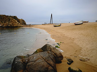 Sandy beach with boats and rocks on Costa Brava