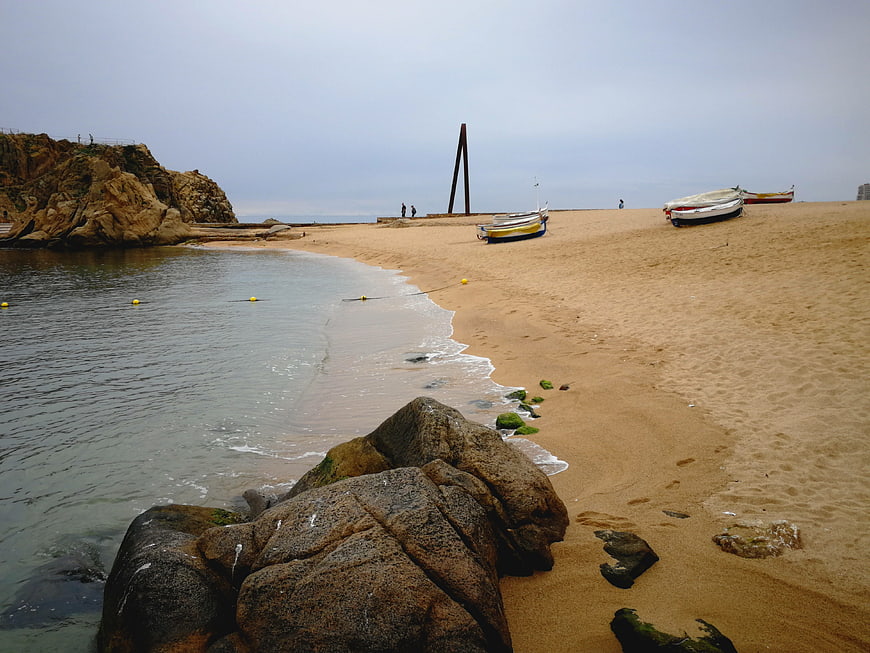 Sandy beach with boats and rocks on Costa Brava