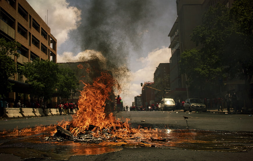 Burning Barricade on City Street with Smoke and Protesters