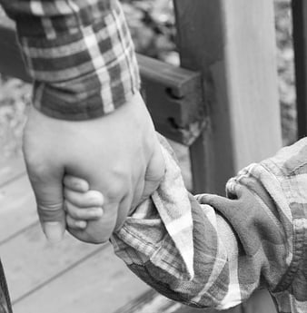 Black and white close-up of adult and child holding hands