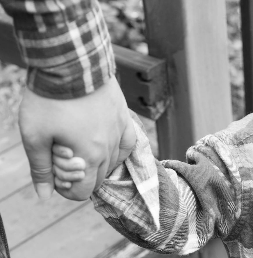Black and white close-up of adult and child holding hands