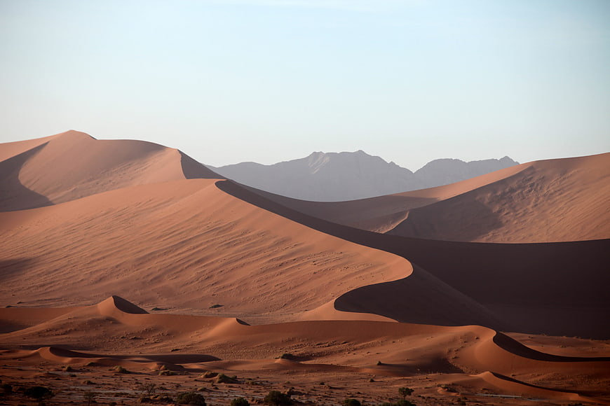 Red sand dunes in Namib desert with distant mountains