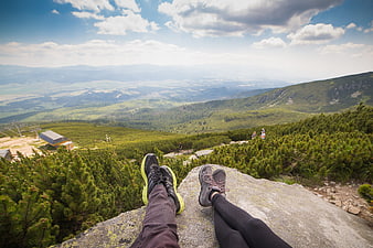 Hikers resting on mountain cliff edge with scenic valley view