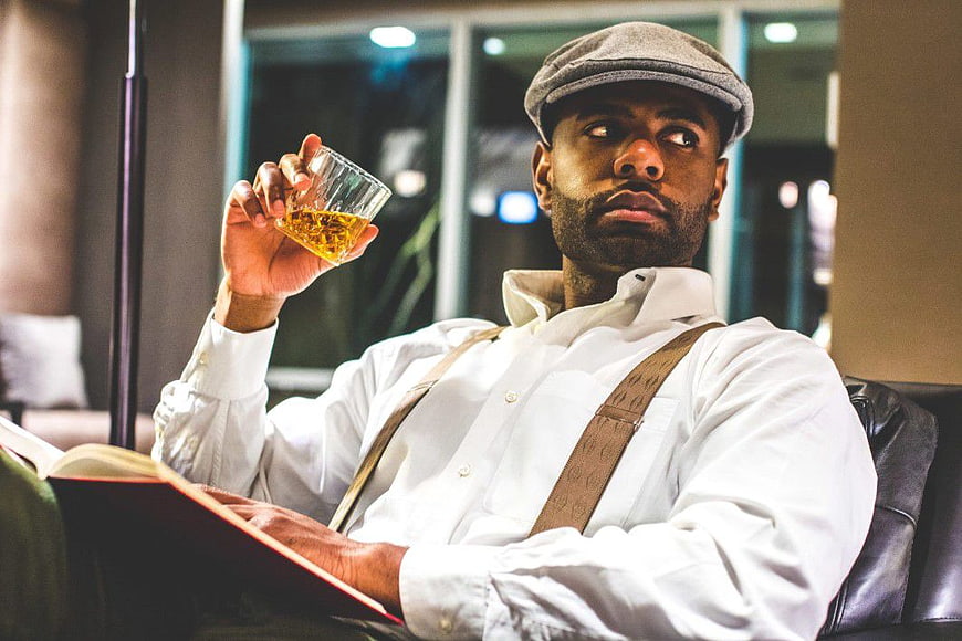 Stylish Man in Cap and Suspenders Drinking Whisky