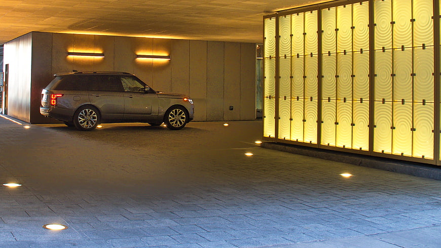 Silver luxury SUV parked in modern illuminated driveway at night