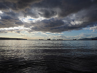 Cargo ships on the ocean under dramatic storm clouds