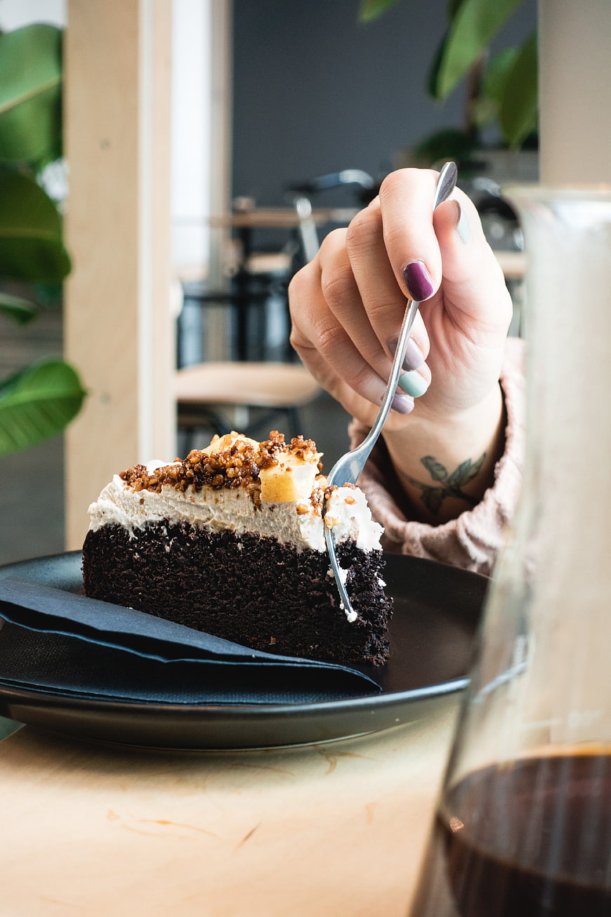 Hand Eating Chocolate Cake Slice in Modern Cafe