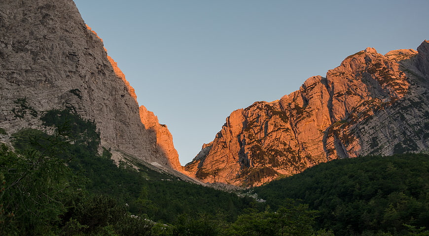 Sunlit Mountain Peaks with Forested Valley Below