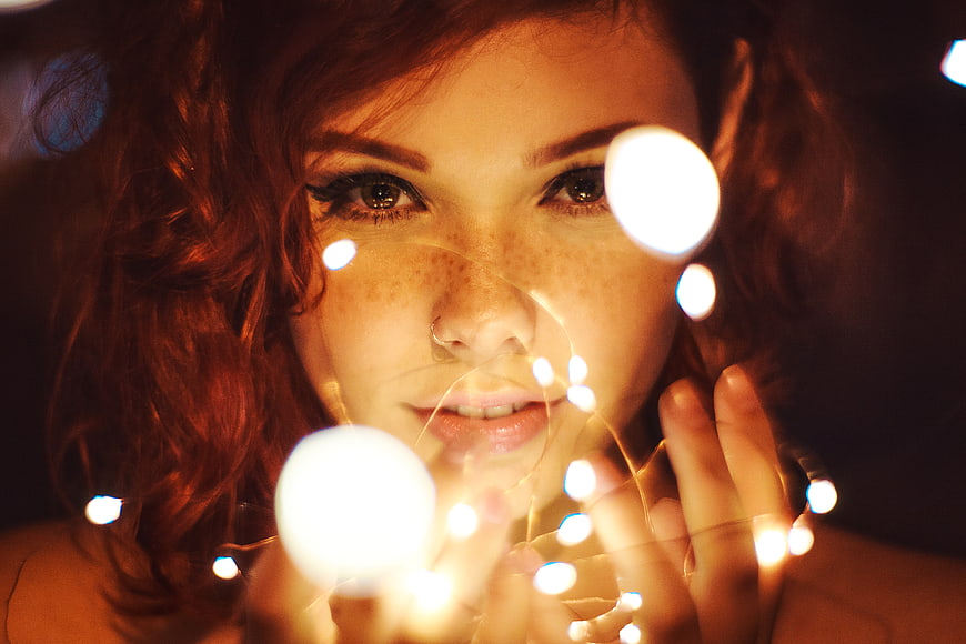 Close-up portrait of woman with fairy lights and bokeh