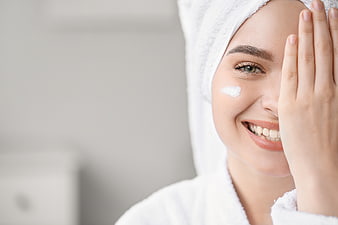 Happy Woman Applying Face Cream with Towel on Head