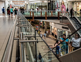 Busy multi-level shopping mall interior with shoppers and escalators