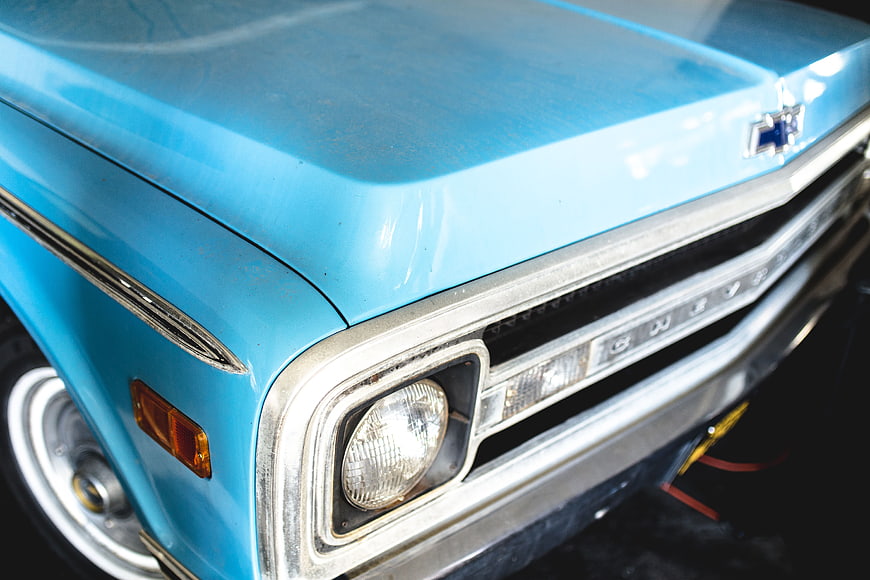 Close-up of vintage blue Chevrolet truck front grille and headlight