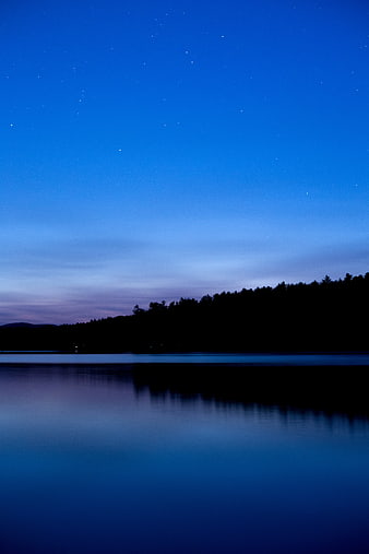 Serene Night Sky Over Calm Lake With Forest Silhouette