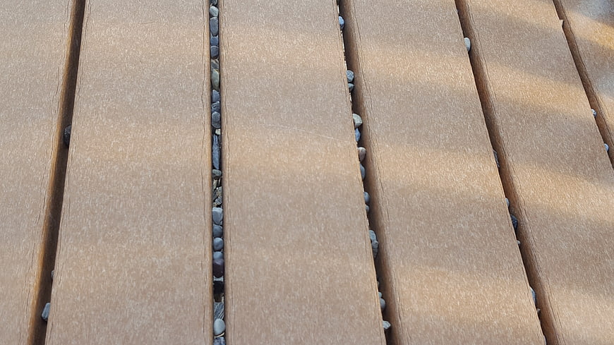 Close-up of wooden deck planks with pebble-filled gaps