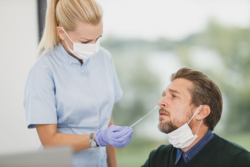 Nurse performing nasal swab test on male patient