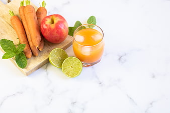 Fresh carrot apple juice with limes on marble background