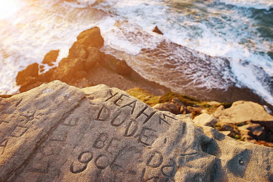 Carved Graffiti on Coastal Rock with Ocean Waves