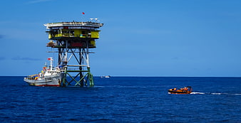 Offshore Platform with Docked Ship and Speedboat on Blue Sea