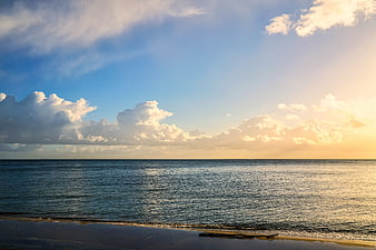 Serene Ocean Sunset with Golden Sky and Fluffy Clouds