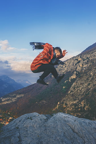 Man jumping on mountain peak with autumn landscape background