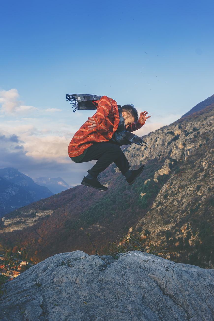 Man jumping on mountain peak with autumn landscape background