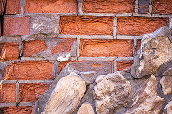 Close-up of weathered red brick and rough stone wall texture