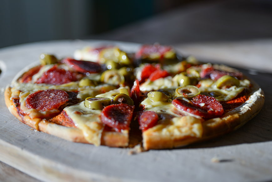 Delicious pepperoni and olive pizza on wooden board