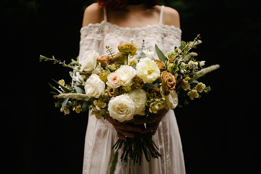 Woman holding rustic white and peach wedding bouquet