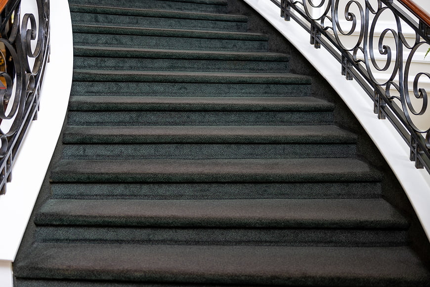 Elegant Carpeted Staircase with Ornate Iron Railing