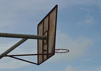 Rusty outdoor basketball hoop against blue sky