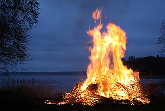 Large Bonfire Burning by Lake at Dusk