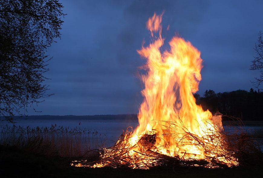 Large Bonfire Burning by Lake at Dusk