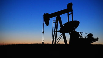 Silhouette of Oil Pump Jack Against Blue Sunset Sky