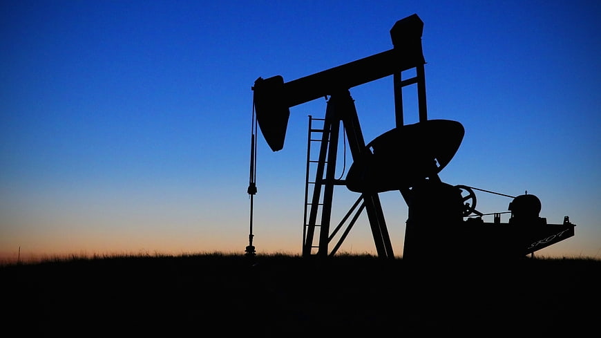 Silhouette of Oil Pump Jack Against Blue Sunset Sky