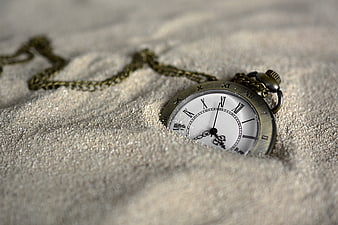 Vintage pocket watch half buried in sand