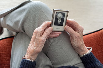 Elderly woman holding framed black and white portrait of deceased husband