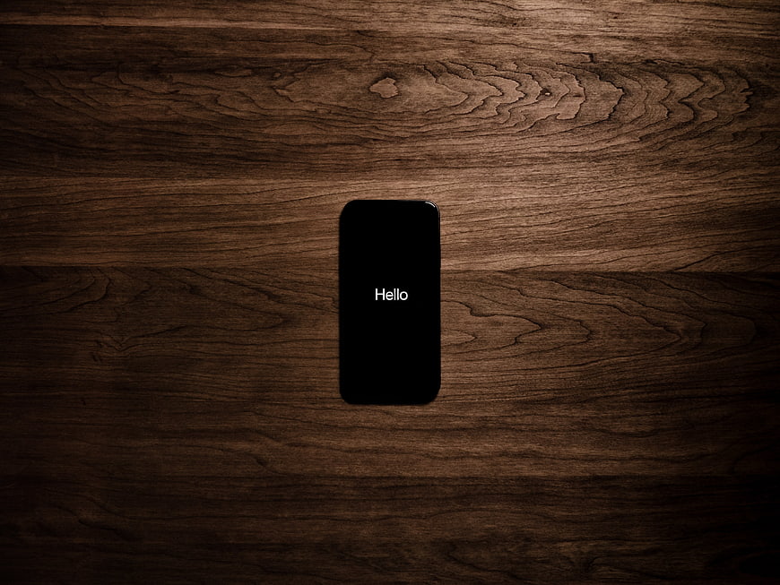 Smartphone with Hello text on dark wood background