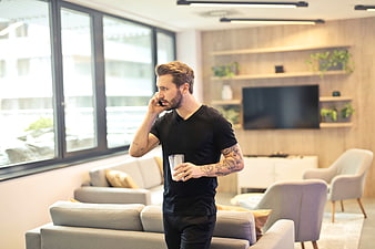 Man with tattoos talking on phone in modern living room